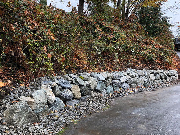 Rockery retaining wall supporting a hillside above a residential road