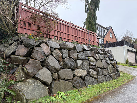 Residential rockery retaining wall with fence on top